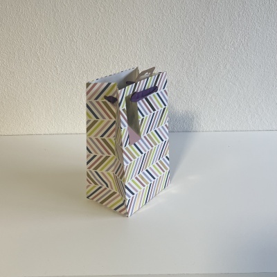 Saco de papel com padrão geométrico multicolorido e cordões roxos