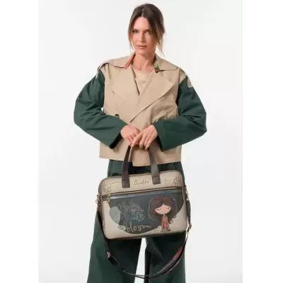 Mala bege e verde com ilustração de rapariga e texto colorido numa mulher com casaco bege e verde