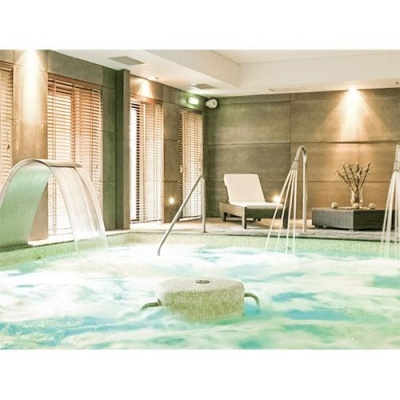 Piscina interior com jatos de água e cadeirão branco em espaço moderno