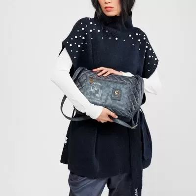 Mulher com camisola preta de pérolas e mala cinzenta acolchoada