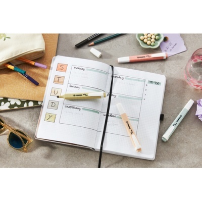 Planner semanal aberto com marcadores e acessórios de escrita em mesa