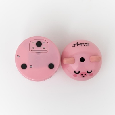 Dispositivos redondos cor-de-rosa, um com rosto de porco e outro com compartimento de bateria, em fundo branco