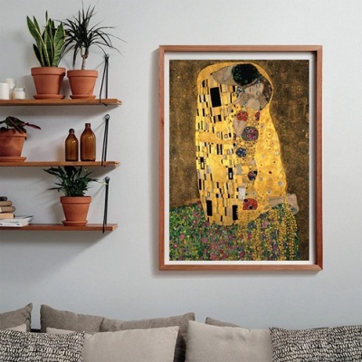 Quadro com reprodução da pintura O Beijo de Gustav Klimt em moldura de madeira numa sala com sofá e prateleiras de plantas