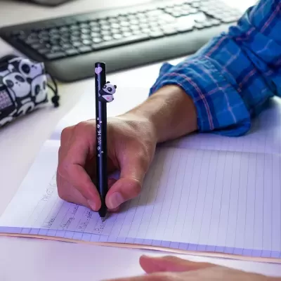 Caneta preta com panda decorativo e texto HUG ME sobre caderno de linhas