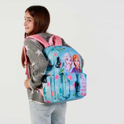 Criança com mochila azul e rosa com personagens de desenhos animados e bolso frontal com texto.