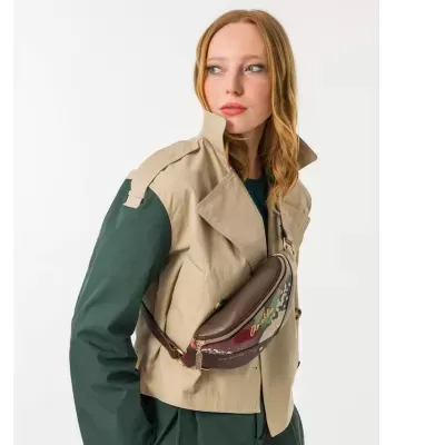 Mulher com casaco bege e verde e bolsa tiracolo marrom com detalhes coloridos