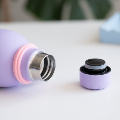 Garrafa térmica lilás com tampa castanho-escuro destacada ao lado numa superfície branca