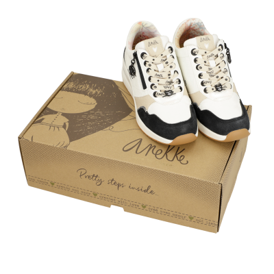Ténis Anekke branco, bege e preto em cima de caixa castanha com texto