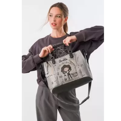 Mala cinzenta com personagem cartoon e texto Anekke segurada por mulher com roupa cinzenta