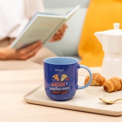 Caneca azul com texto e imagens de pizza numa bandeja com croissants e colher