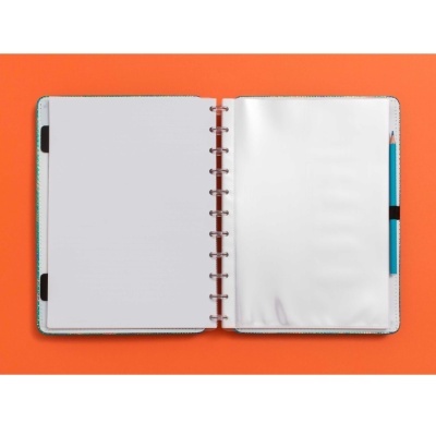 Caderno de argolas aberto com folhas brancas e lápis azul sobre fundo laranja