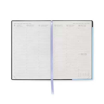 Agenda aberta com páginas brancas, linhas e datas, fita marcador lilás, capa preta e canto azul.