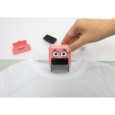 Carimbo rosa com desenho de olhos colocado sobre t-shirt branca.