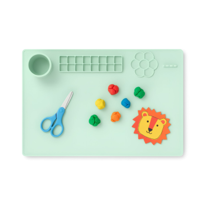 Tapete de silicone verde com tesoura azul, bolas coloridas de massa e recorte de leão