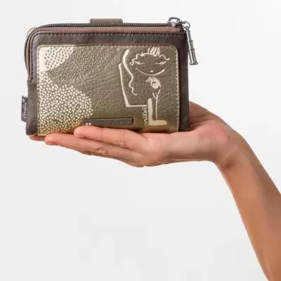 Carteira castanha e dourada com desenho de rosto e etiqueta Anello nas mãos