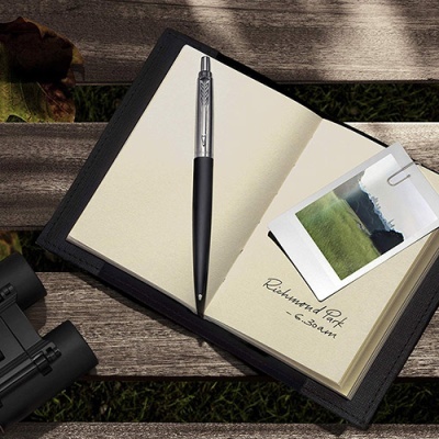 Caderno aberto com caneta, foto Polaroid e texto Richmond Park - 6.30am sobre uma banca de madeira