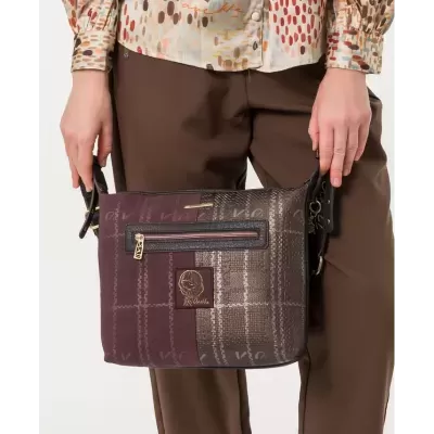 Bolsa quadrada castanha e cinza com fecho e etiqueta frontal, sendo segurada por pessoa
