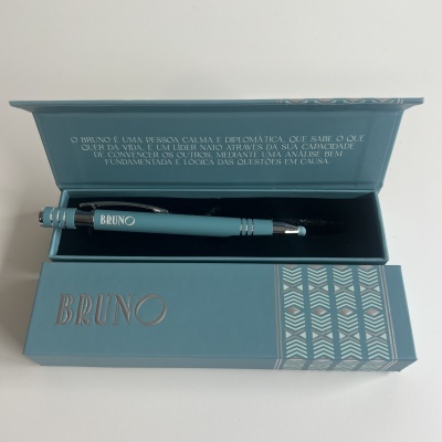 Caneta azul turquesa com nome BRUNO numa caixa azul com padrão prateado