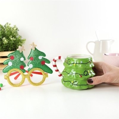 óculos de árvore de Natal dourados e caneca verde de árvore de Natal na mesa