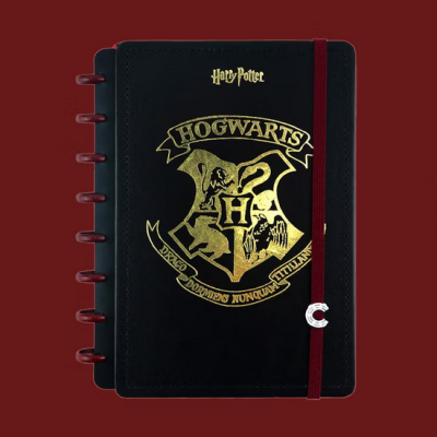 Caderno preto com gravação dourada do brasão de Hogwarts e elástico vermelho
