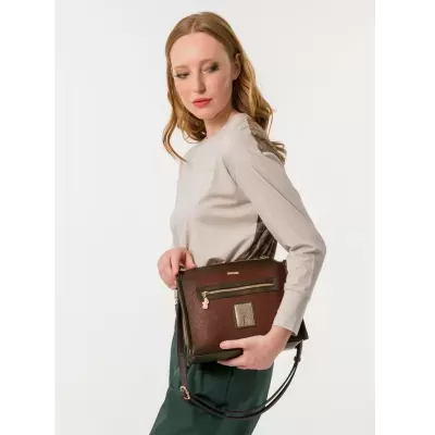 Mulher segurando mala castanha com padrão gravado e detalhes dourados