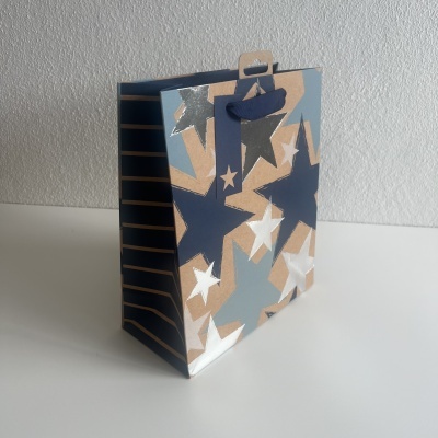 Saco de presente de papel com padrão de estrelas coloridas e alças de fita azul escuro
