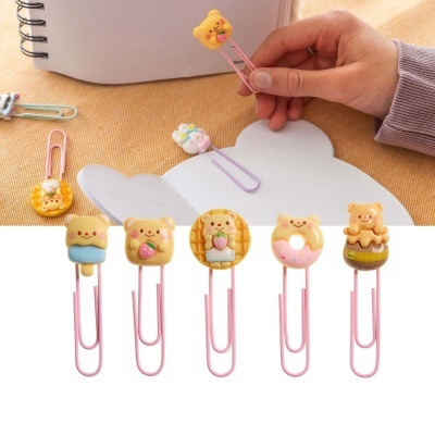 Clips de papel decorativos com ursinhos coloridos e mesa com caderno branco