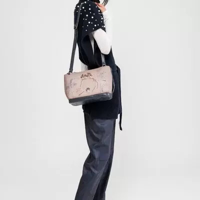 Mulher com mala bege estampada e roupa preta e branca