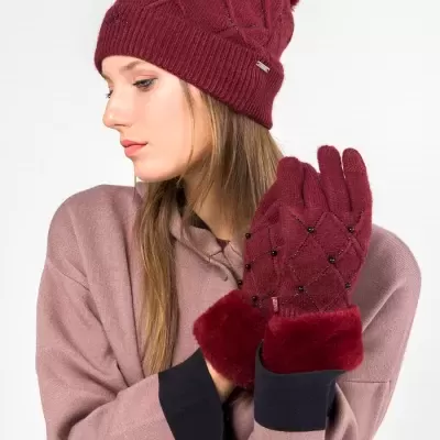 Conjunto de gorro e luvas femininas vermelhas com pompom e texturas, vestida por mulher com casaco castanho claro.