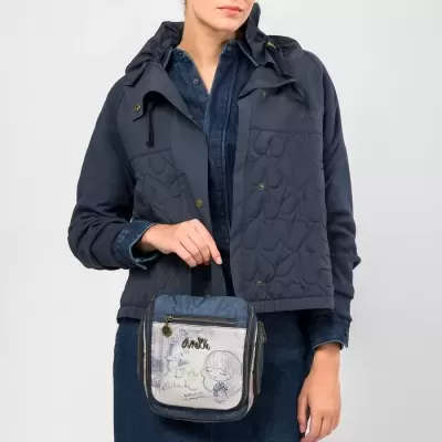 Mulher com casaco acolchoado azul escuro e vestido jeans segurando bolsa azul com imagens e texto Amore