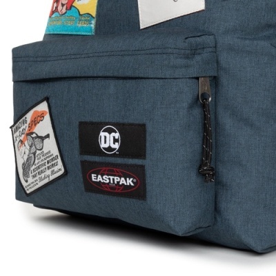 Bolso frontal de mochila azul com patches DC e EASTPAK e um patch com desenho e texto.