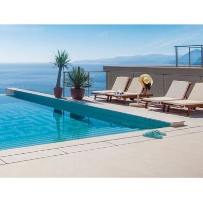 Piscina com cadeiras de madeira e vista para o mar