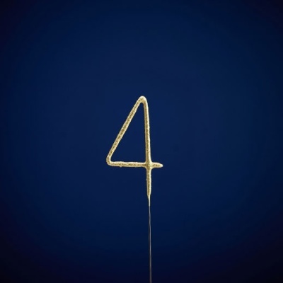 Vela dourada em forma do número 4 sobre fundo azul