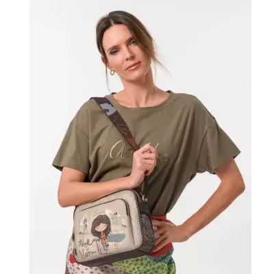Saco tiracolo bege com ilustração de menina, t-shirt verde-oliva com texto bordado e saia colorida com padrão