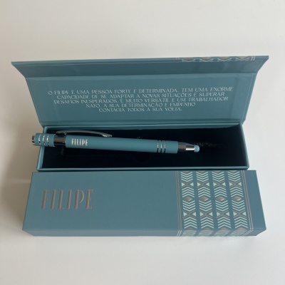 Caneta azul turquesa numa caixa azul com padrão geométrico e texto 'FILIPE'