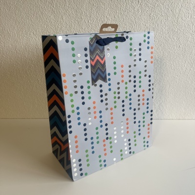 Saco de presente de papel com padrão colorido de bolinhas e zig-zag e alça azul