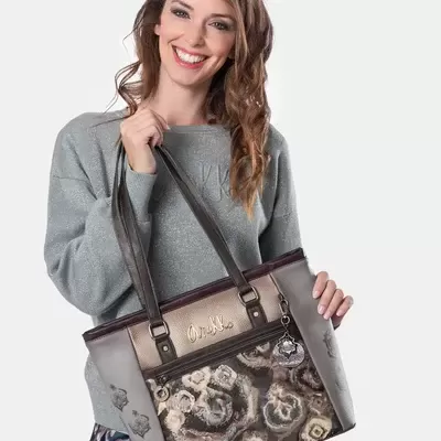 Mulher a segurar uma mala de mão com padrão floral e alças castanhas