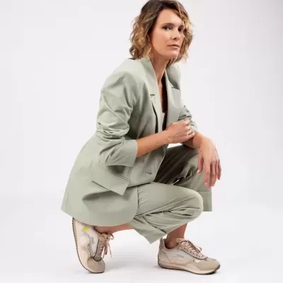 Mulher com fato verde claro e sapatilhas bege