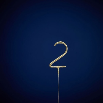 Vela dourada em forma do número 2 com fundo azul escuro