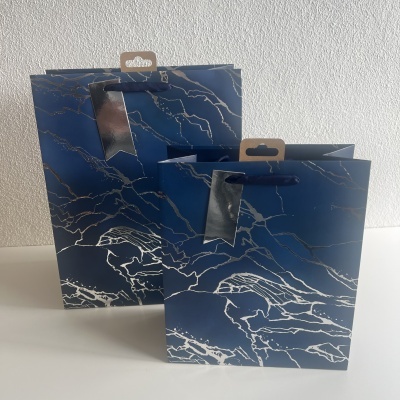 Sacolas de papel azul escuro com padrão branco mármore e alças azuis