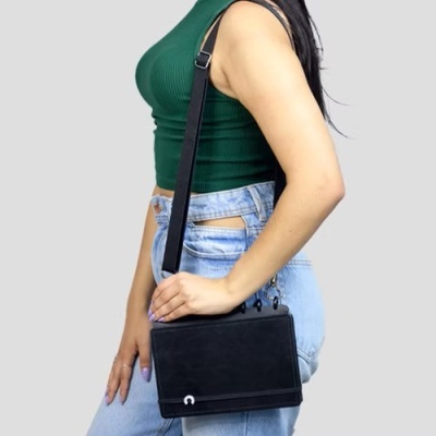 Mulher com top verde, calças de ganga azuis e mala preta de tiracolo