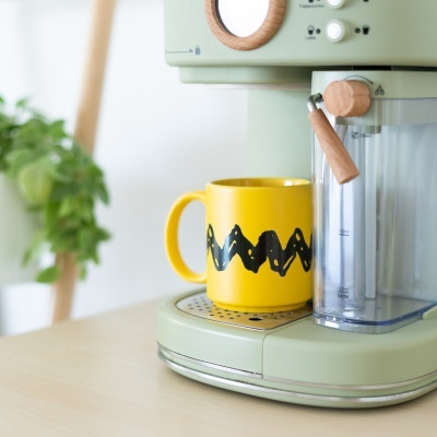 Máquina de café verde claro e chávena amarela com padrão preto zig-zag