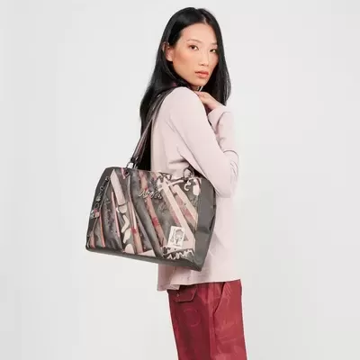 Mulher com camisola creme e calças vermelhas com mala de ombro estampada