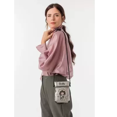 Mulher com camisa rosa e calças cinzentas a usar mala pequena prateada com ilustração e texto