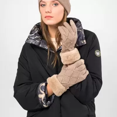 Mulher com gorro e luvas castanhas, casaco preto e saia com padrão abstrato.