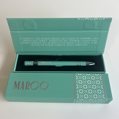 Conjunto com caneta verde-água em caixa decorada verde-água com padrão geométrico e texto em português