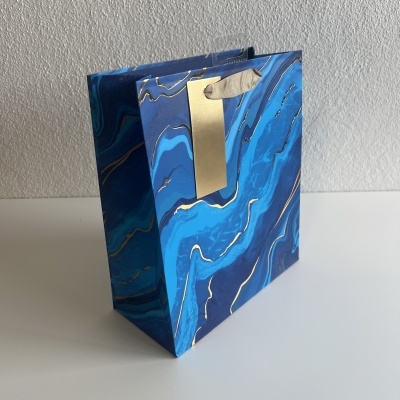 saco de presente azul marmoreado com etiqueta dourada