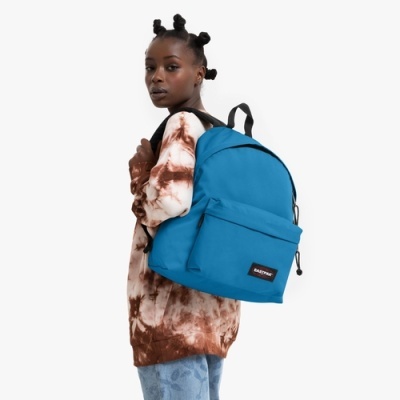 Mochila azul EASTPAK com bolso frontal usada por mulher com camisola tie-dye castanho e branco