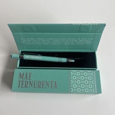 Conjunto de caneta e caixa verde com texto MÃE TERNARENTA e padrões geométricos