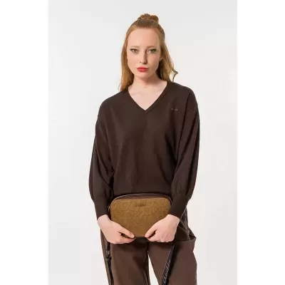 Mulher com camisola castanha e mala castanha clara com padrão